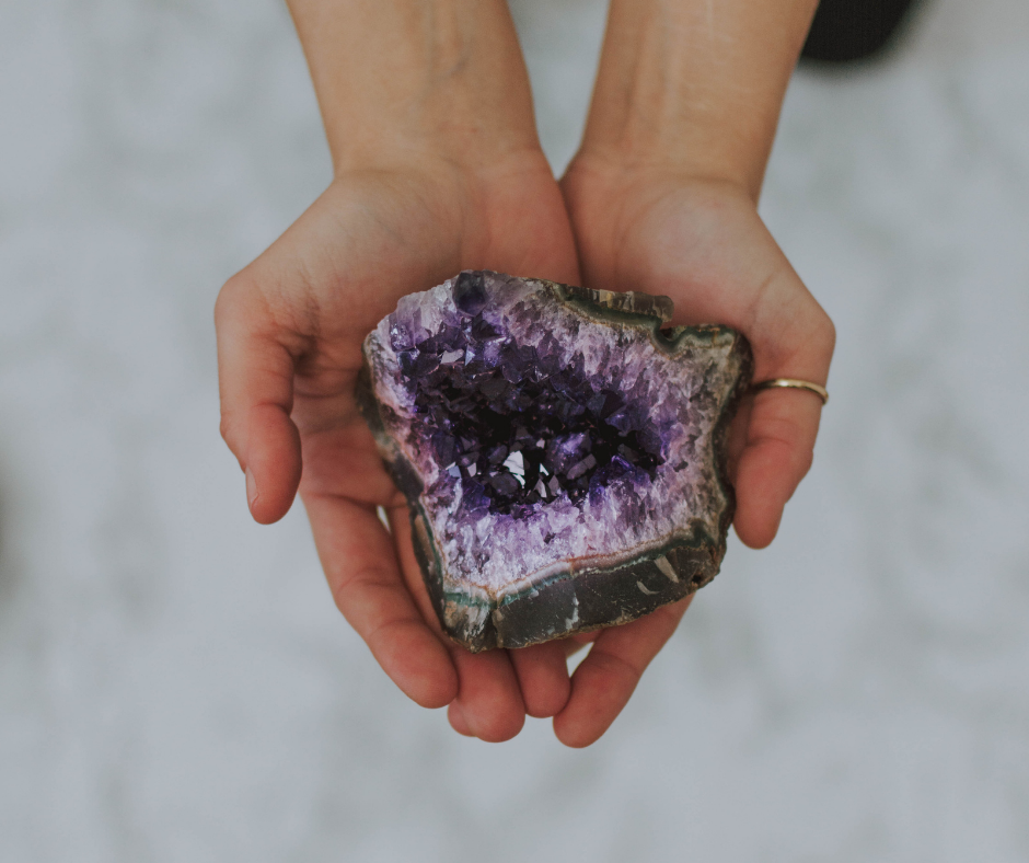 Hands holding a purple colored geode.