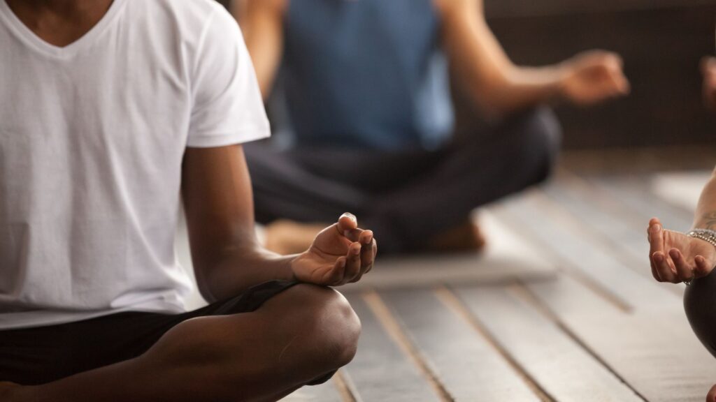 image of a group of people sitting on the floor in a criss cross yoga seated position