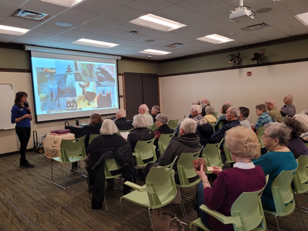 Image of a group of people in front of a screen projector with a person standing next to it.